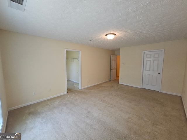 spare room featuring a textured ceiling and light colored carpet