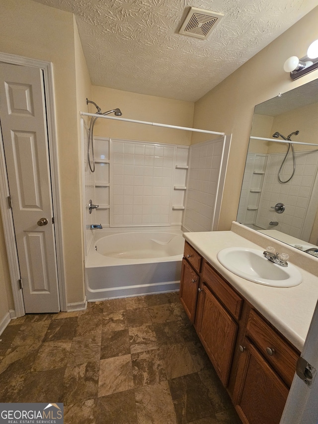 bathroom with vanity, tiled shower / bath combo, and a textured ceiling