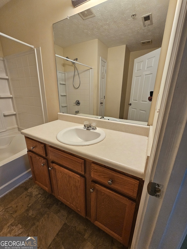 bathroom featuring vanity, tiled shower / bath combo, and a textured ceiling