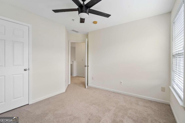 unfurnished bedroom with light colored carpet, multiple windows, and ceiling fan