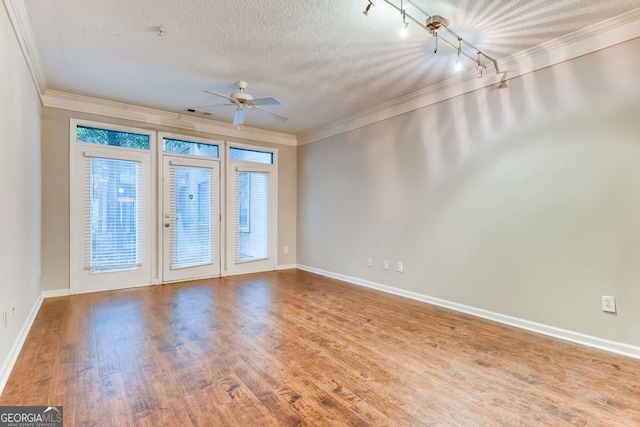 empty room with wood-type flooring, a textured ceiling, and ornamental molding