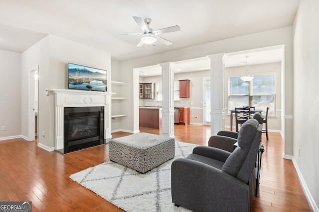 living room featuring wood-type flooring, built in features, and ceiling fan