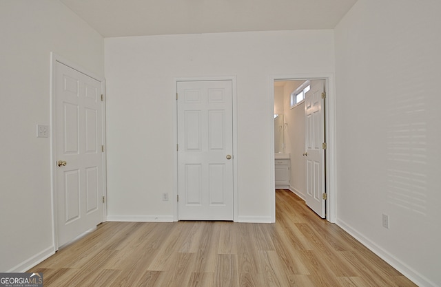 unfurnished bedroom featuring ensuite bathroom and light hardwood / wood-style floors