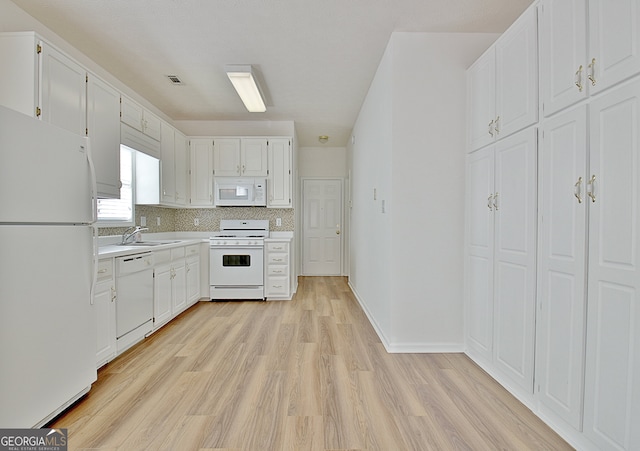 kitchen featuring white appliances, backsplash, white cabinets, sink, and light hardwood / wood-style flooring