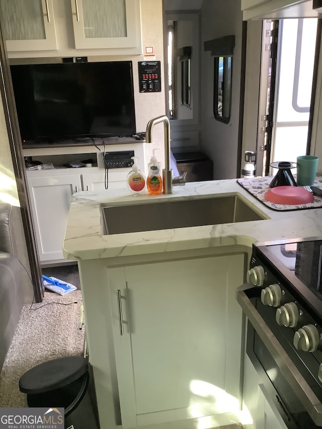 kitchen with electric range oven, light stone countertops, and sink