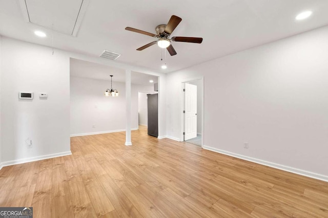 empty room featuring light hardwood / wood-style flooring and ceiling fan with notable chandelier