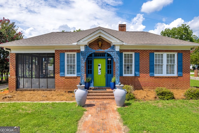 view of front facade with a sunroom and a front lawn