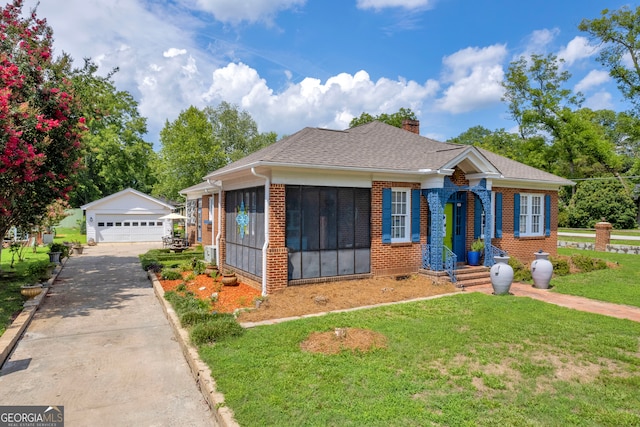 view of front facade with a sunroom, an outbuilding, a front yard, and a garage