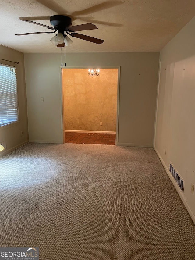 empty room with ceiling fan, carpet, and a textured ceiling