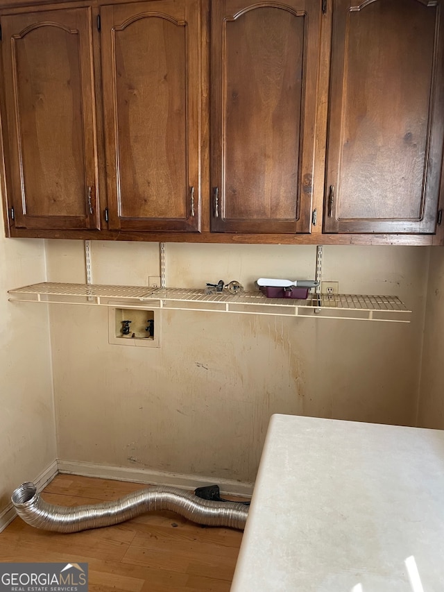 clothes washing area with cabinets, hardwood / wood-style floors, and washer hookup