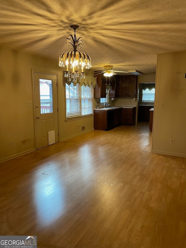 kitchen with ceiling fan with notable chandelier, hanging light fixtures, a textured ceiling, light hardwood / wood-style floors, and dark brown cabinetry