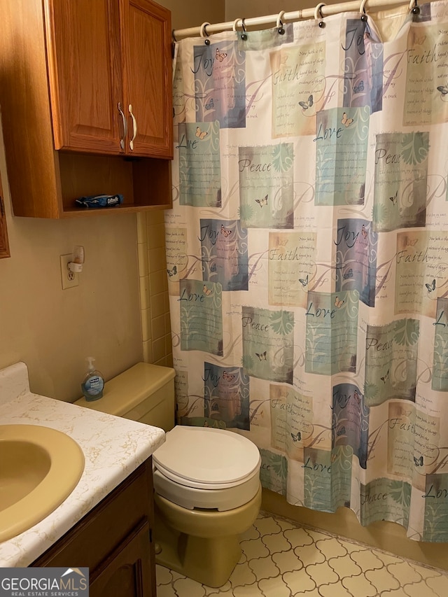 bathroom featuring tile patterned flooring, vanity, toilet, and walk in shower