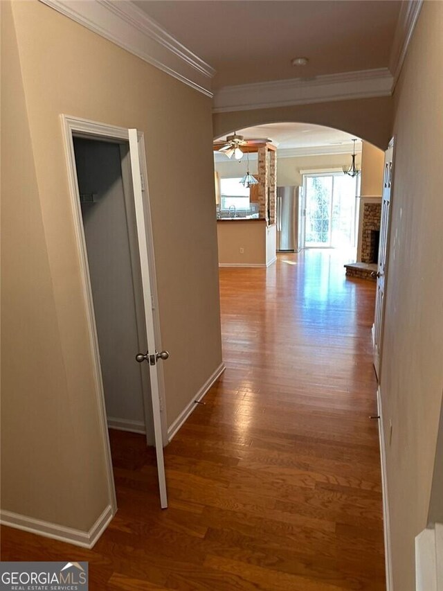 hallway with wood-type flooring and ornamental molding