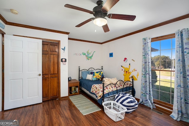 bedroom with ceiling fan, dark hardwood / wood-style flooring, crown molding, and a closet