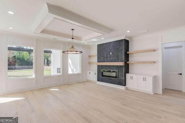 unfurnished living room featuring a fireplace, light wood-type flooring, a tray ceiling, and a notable chandelier