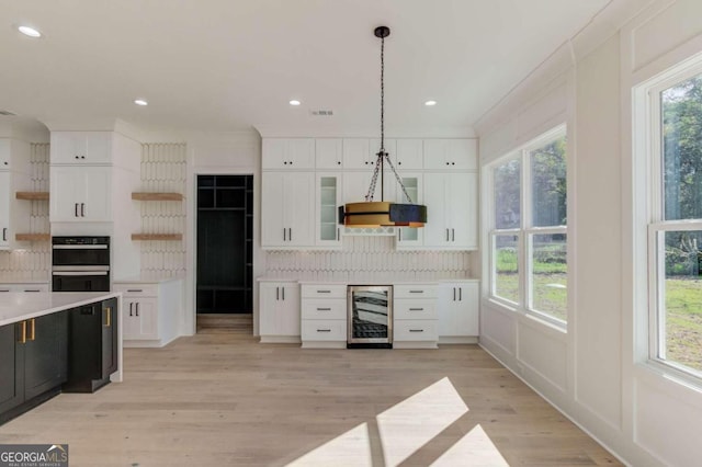 kitchen featuring white cabinets, light hardwood / wood-style flooring, decorative backsplash, decorative light fixtures, and beverage cooler