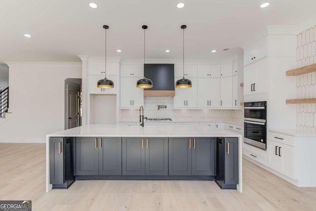 kitchen with stainless steel double oven, extractor fan, decorative light fixtures, light hardwood / wood-style floors, and white cabinetry