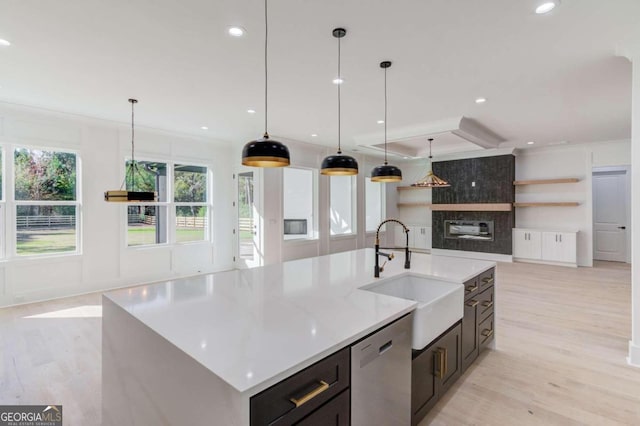 kitchen featuring a large island, sink, light hardwood / wood-style flooring, stainless steel dishwasher, and pendant lighting