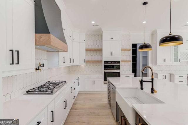 kitchen featuring stainless steel appliances, backsplash, decorative light fixtures, white cabinets, and custom range hood