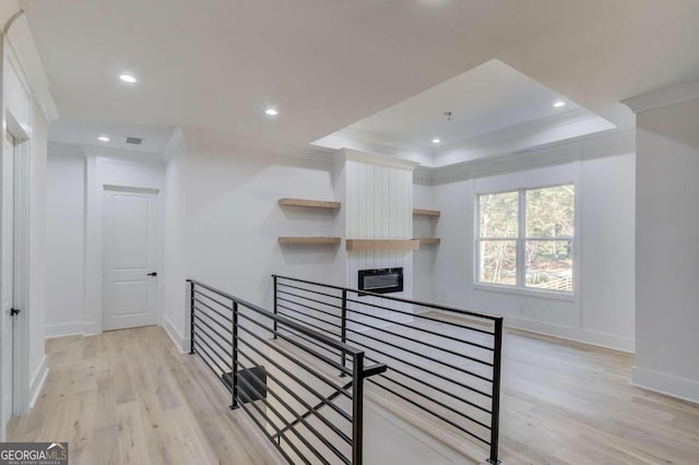 hallway featuring a raised ceiling, light hardwood / wood-style floors, and ornamental molding