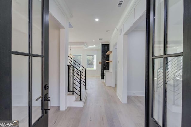 entrance foyer with crown molding, french doors, and light wood-type flooring