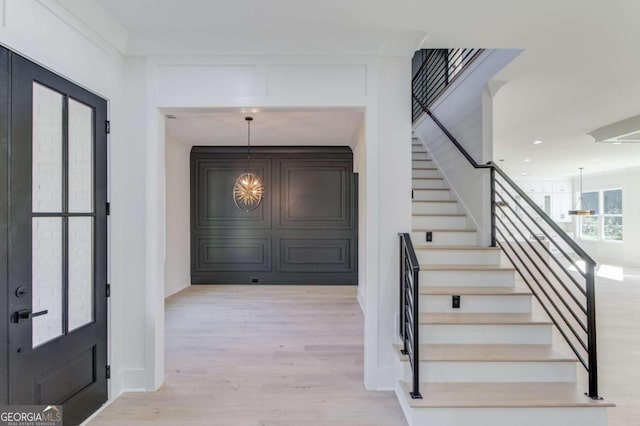 entryway with french doors, an inviting chandelier, and light wood-type flooring