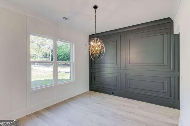 unfurnished dining area with plenty of natural light, a chandelier, and light hardwood / wood-style flooring