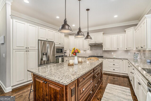 kitchen featuring white cabinetry, hanging light fixtures, stainless steel appliances, dark hardwood / wood-style floors, and a kitchen island