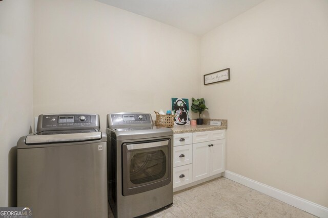 washroom with washer and dryer and cabinets