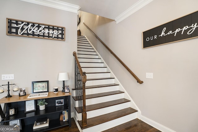 staircase with crown molding, baseboards, and wood finished floors