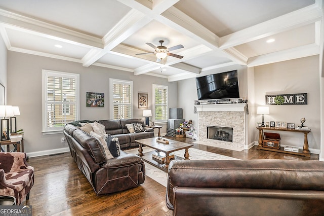 living room with dark wood-style floors, beam ceiling, a stone fireplace, and baseboards