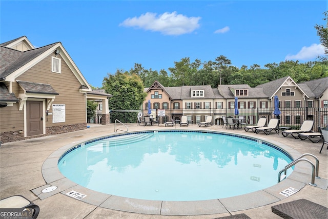 view of swimming pool featuring a patio area, a residential view, and fence