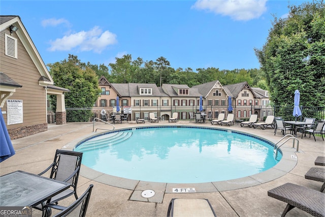 view of swimming pool with a residential view, a patio area, and fence