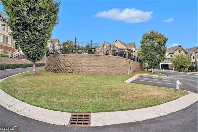 view of community with uncovered parking, a yard, and fence