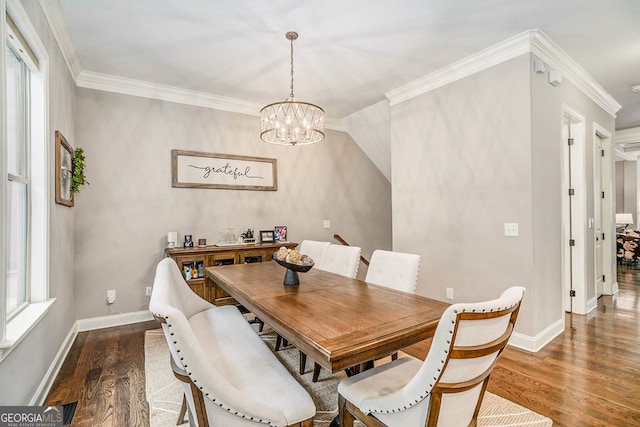 dining room featuring dark hardwood / wood-style flooring, crown molding, and an inviting chandelier