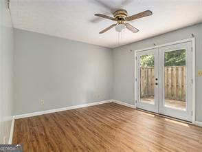 empty room featuring ceiling fan, wood-type flooring, and french doors