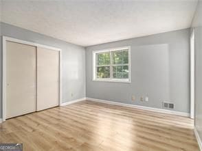 unfurnished bedroom with light wood-type flooring and a closet