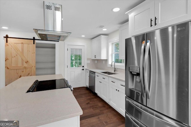 kitchen featuring a barn door, appliances with stainless steel finishes, island range hood, dark hardwood / wood-style flooring, and white cabinetry