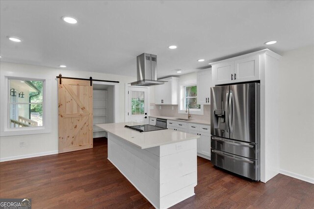 kitchen featuring black appliances, a barn door, white cabinets, and ventilation hood