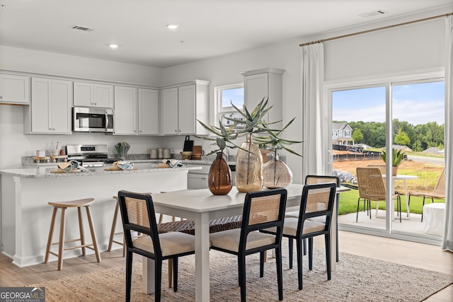 kitchen featuring white cabinetry, light stone counters, light wood-type flooring, and appliances with stainless steel finishes