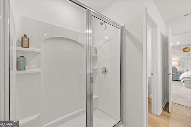 bathroom with hardwood / wood-style floors and an enclosed shower