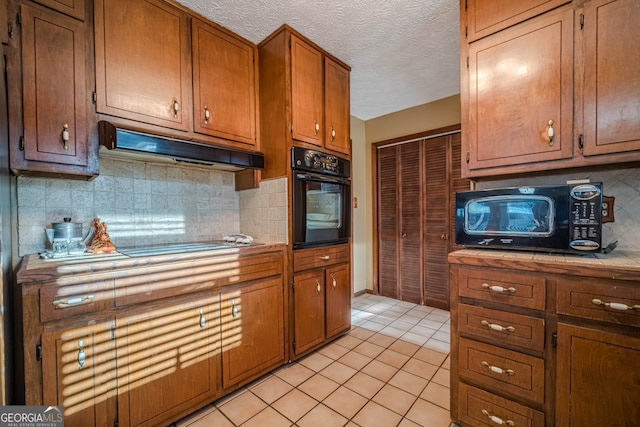 kitchen featuring light tile patterned flooring, decorative backsplash, a textured ceiling, and black appliances