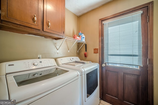 laundry room featuring cabinets, a textured ceiling, and separate washer and dryer