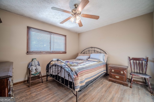 bedroom with ceiling fan, a textured ceiling, and hardwood / wood-style flooring