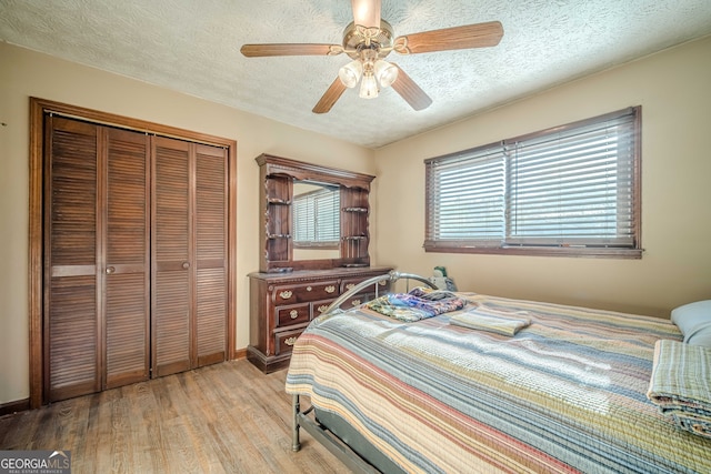 bedroom with a textured ceiling, a closet, light hardwood / wood-style flooring, and ceiling fan