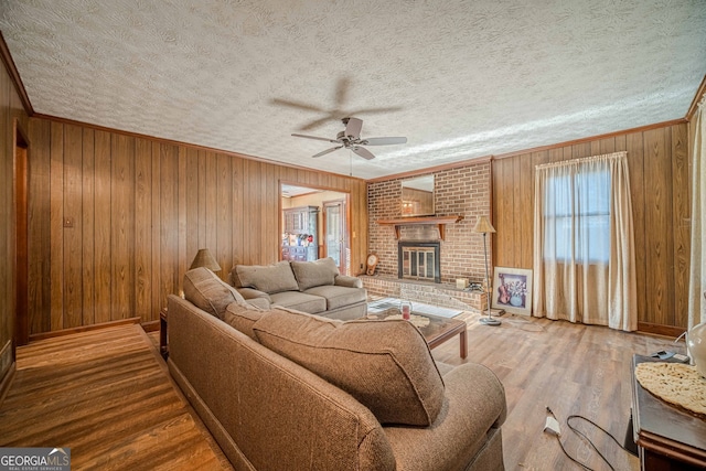 living room with hardwood / wood-style floors, wood walls, a fireplace, and a textured ceiling