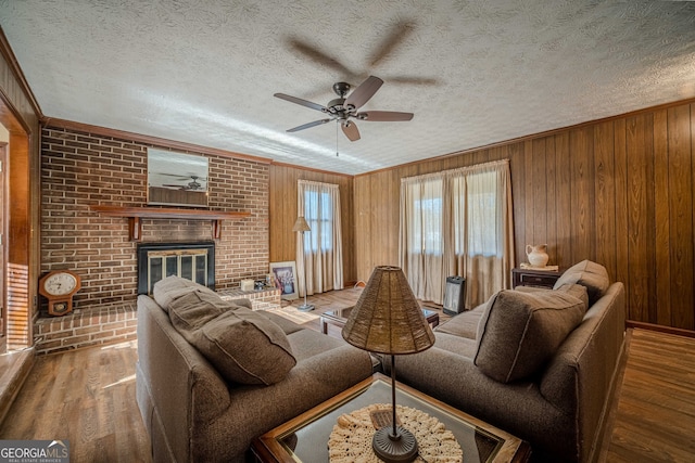 living room with ceiling fan, wood walls, wood-type flooring, and a textured ceiling