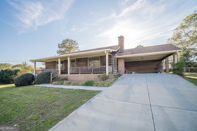 view of front facade with a carport, covered porch, and a front lawn