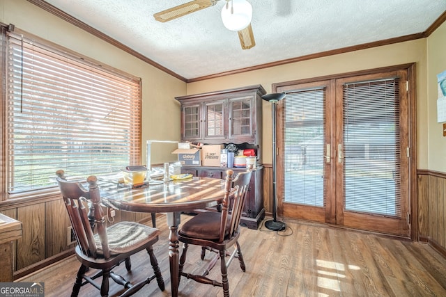 dining room featuring wood walls, crown molding, a textured ceiling, and hardwood / wood-style flooring