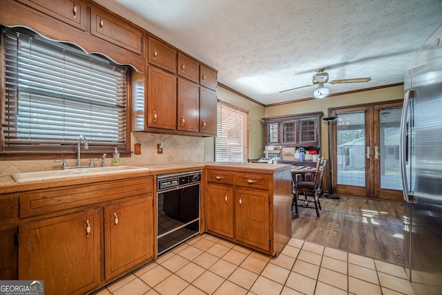 kitchen featuring dishwasher, sink, stainless steel fridge, light wood-type flooring, and ornamental molding